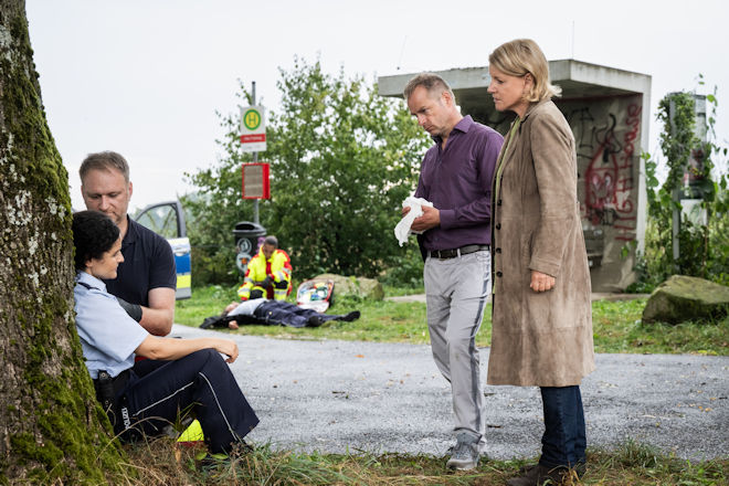Marie Brand (Mariele Millowitsch, r.) und Jürgen Simmel (Hinnerk Schönemann, 2.v.r.) befragen am Tatort die Kollegin Claudia Baum (Nagmeh Alaei, l.) zu dem Schützen.
