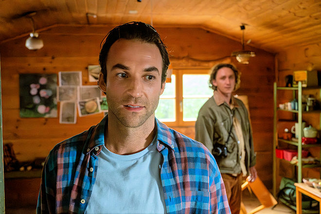 Herzkino-Film "Baumgeflüster": Förster Yascha (Linus Schütz, l.) kann es nicht fassen: Der attraktive Fotograf Mats (Aaron Friesz, r.) ist ausgerechnet der gesuchte Erbe des Privatwaldes, den seine Chefin für den geplanten Nationalpark erwerben will.