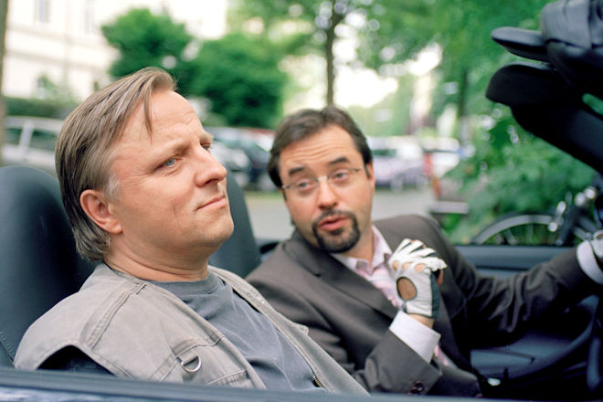 M&uuml;nster-Tatort "Eine Leiche zu viel": Rechtsmediziner Prof. Karl-Friedrich Boerne (Jan Josef Liefers, re.) f&auml;hrt den am Fu&szlig; l&auml;dierten Kommissar Frank Thiel (Axel Prahl) mit dem Auto zur Arbeit.