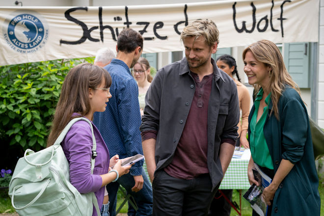 Herzkino-Film "Wolf" aus der Reihe "Neuer Wind im Alten Land": Laila (Elsa Krieger, l.) soll sich ihren &Auml;ngsten stellen und kommt mit ihrem Vater Paul (Steve Windolf, M.) zur Info-Veranstaltung der Jorker zum Streitthema "Der Wolf". Dort treffen sie auf Beke (Felicitas Woll, r.), die einen Artikel f&uuml;r die "Altl&auml;nder Zeitung" schreibt.