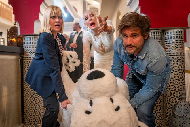 Julianes (Désirée Nick, M.) Hochzeitsfeier läuft vollkommen aus dem Ruder, als Nina (Henrike Fehrs, l.) und Tom (Tom Beck) versuchen, die Leiche im Eisbärkostüm aus der Location zu schaffen.