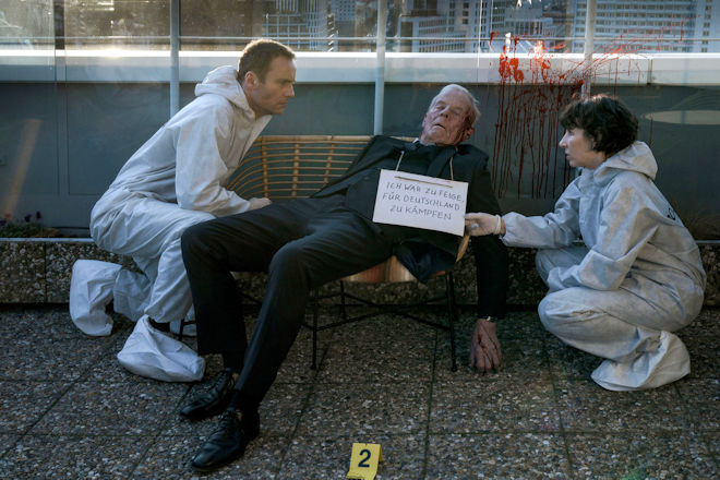 Berlin-Tatort "Ein paar Worte nach Mitternacht": Nina Rubin (Meret Becker) und Robert Karow (Mark Waschke, li.) finden Klaus Keller (Rolf Becker) an seinem 90. Geburtstag tot auf. Um seinen Hals hängt eine seltsame Nachricht.