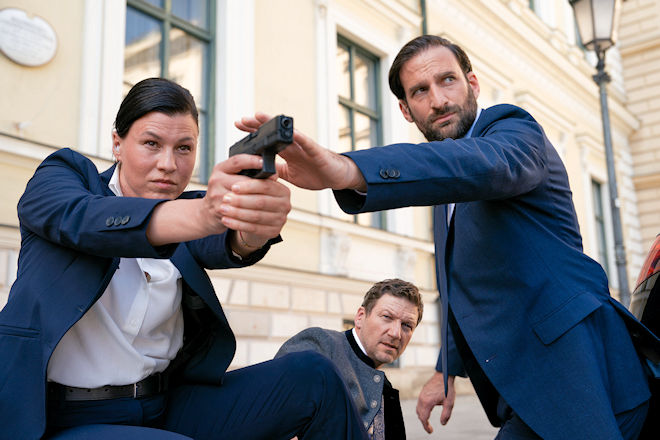 Freitagskrimi "Die Chefin - Hardliner": Staatssekret&auml;r Thomas Farber (Thomas Unger, M.) und die Personensch&uuml;tzer des LKA, Mascha Turger (Tanja Hirner, l.) und Wolfgang M&uuml;ritz (Matthias Weidenh&ouml;fer, r.), stehen vor dem Parlamentsgeb&auml;ude unter Beschuss.