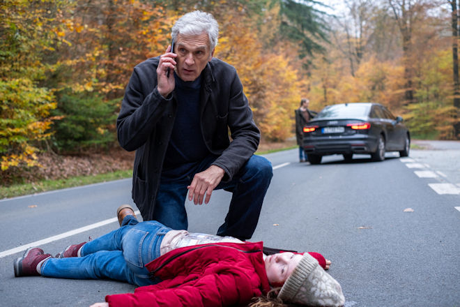 Robert Anders (Walter Sittler) kniet vor Hannah Brunner (Laeni Geiseler), die am Boden liegt und von Annika Wagner (Nurit Hirschfeld) angefahren wurde.