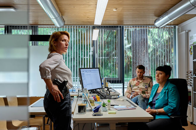 Freitagskrimi "Mordufer - Die große Gier": Kriminalkommissarin Doro Beitinger (Franziska Weisz, l.) spricht im Einwohnermeldeamt mit Vidan Pavlovic (Dražen Pavlović, M.) und dessen Chefin Katrin Glaunsinger (Beate Constanze Pitronik, r.). Warum musste die Kollegin der beiden sterben?